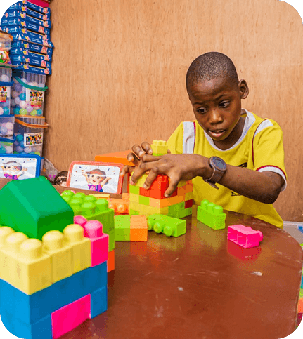 Young boy focused on building with colorful toy blocks at a table.